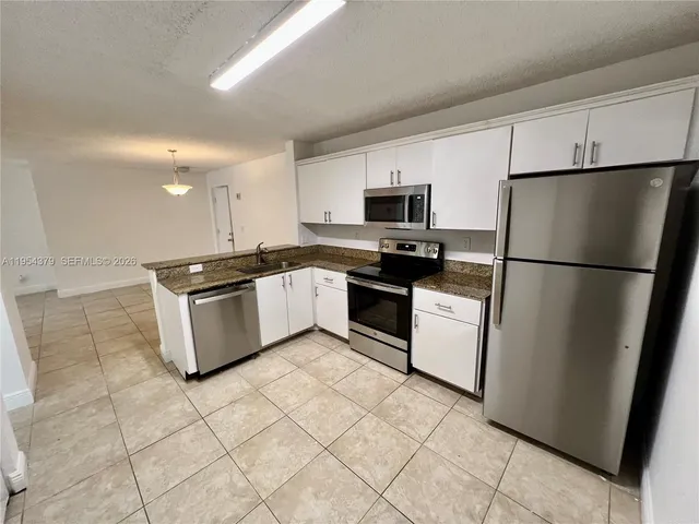 a kitchen with stainless steel appliances granite countertop a stove a sink dishwasher a refrigerator and a microwave