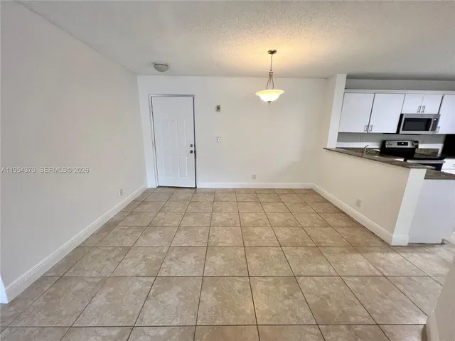 an empty room with kitchen view and a window