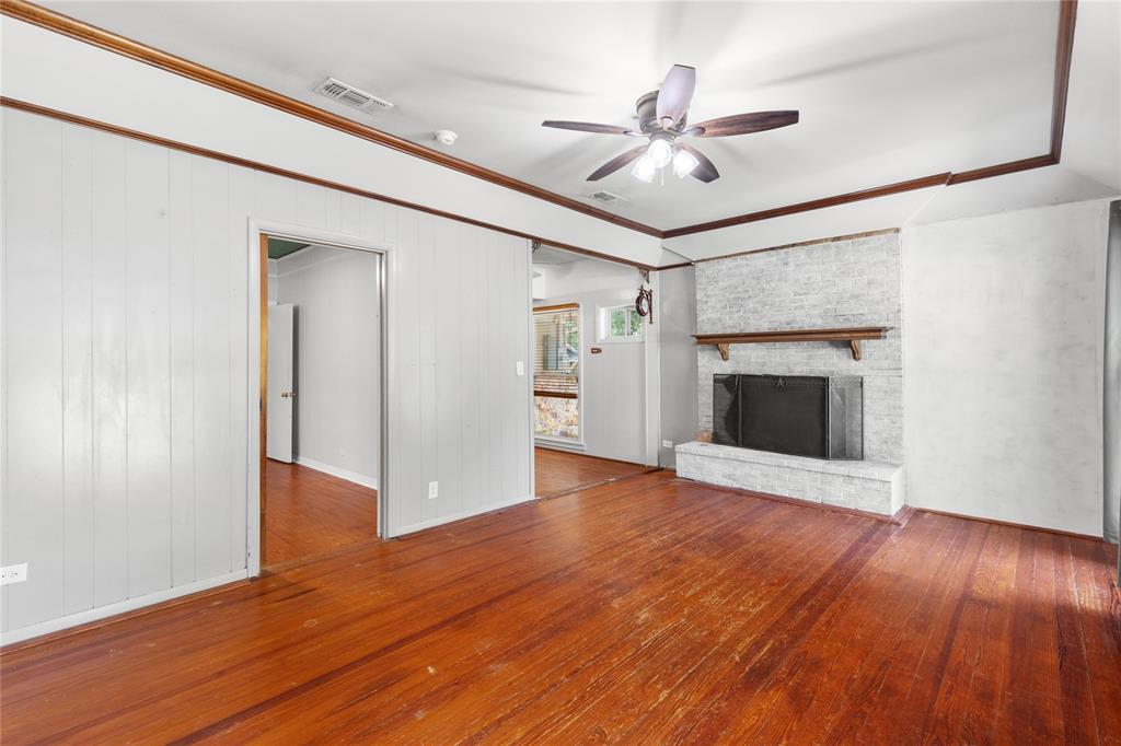 1005 Jernigan Street Commerce, TX 75428 - Photo 5 of 40 Main family room with original hardwood floors and lovely wood burning fireplace with raised brick hearth!