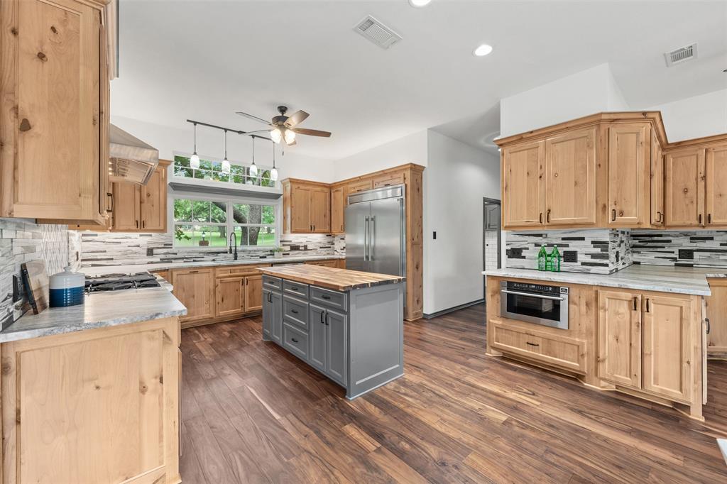 3091 Rockbridge Road McGregor, TX 76657 - Photo 5 of 40 a kitchen with stainless steel appliances kitchen island granite countertop a stove a sink and a refrigerator