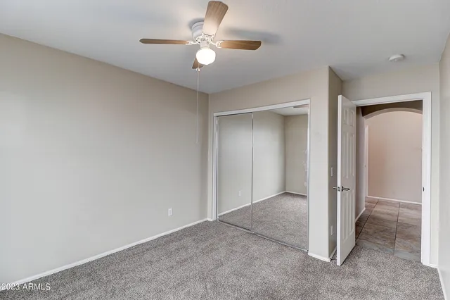 an empty room with a ceiling fan and a window