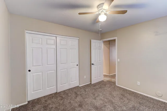 a view of an empty room and chandelier fan