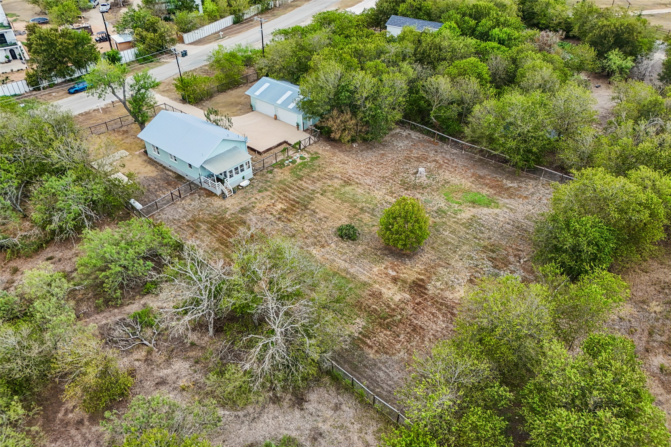 372 Old Lockhart Road Lockhart, TX 78644 - Photo 31 of 40 Mature trees surround a metal-roofed cottage with outbuildings on a spacious fenced lot.