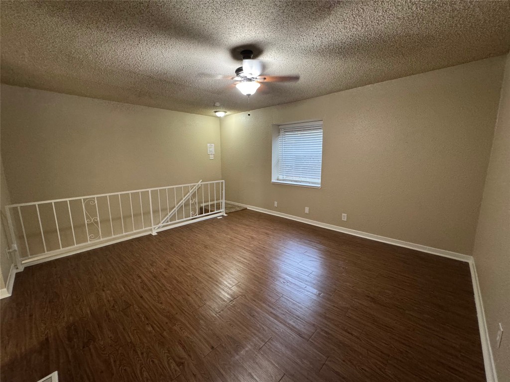 5006 West Wind Trail, Unit 104 Austin, TX 78745 - Photo 15 of 20 an empty room with wooden floor chandelier fan and windows