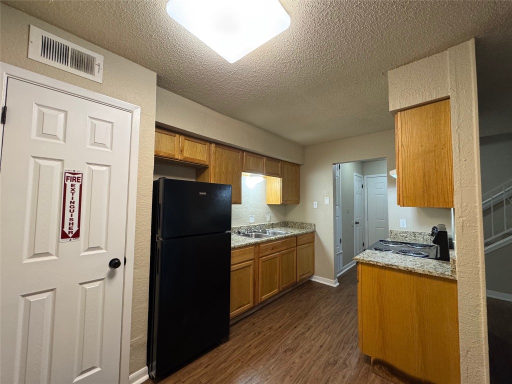 5006 West Wind Trail, Unit 104 Austin, TX 78745 - Photo 5 of 20 a kitchen with granite countertop stainless steel appliances a refrigerator a stove and a refrigerator