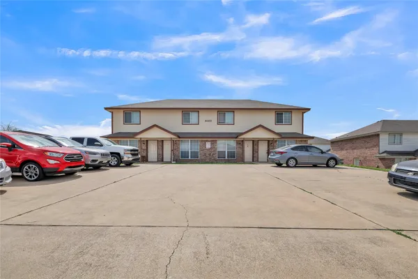 a front view of a house with parking yard and a car