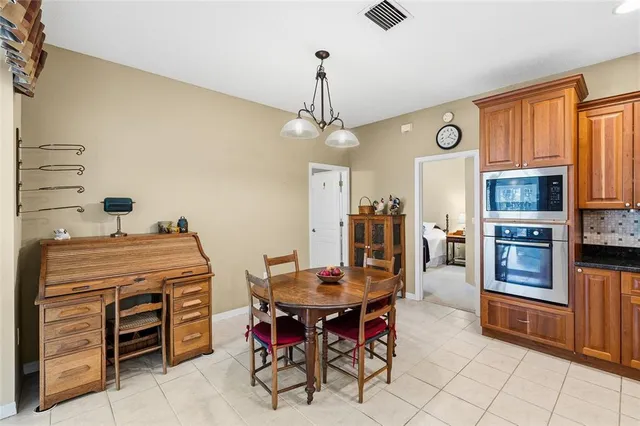 a open kitchen with stainless steel appliances granite countertop a stove top oven a refrigerator a dining table and chairs with wooden floor