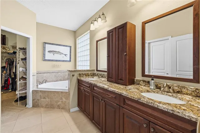 a bathroom with a granite countertop double vanity sink and a bathtub