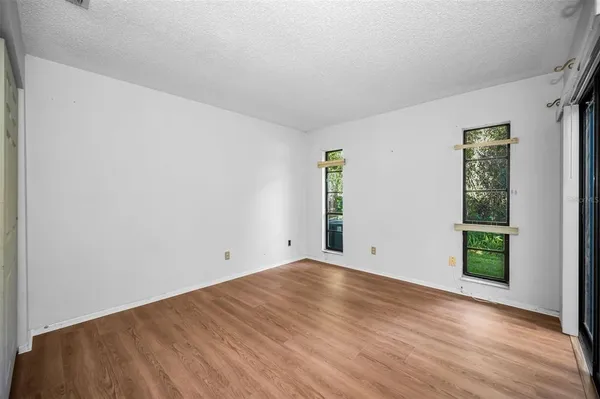 an empty room with wooden floor closet and windows