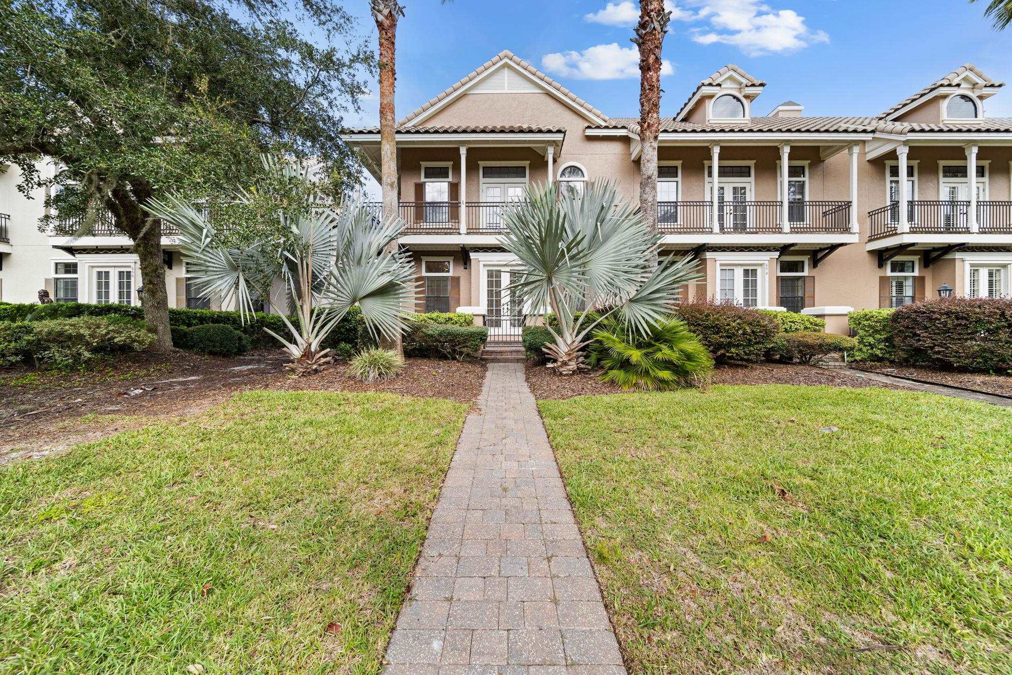 a front view of a house with a yard and potted plants