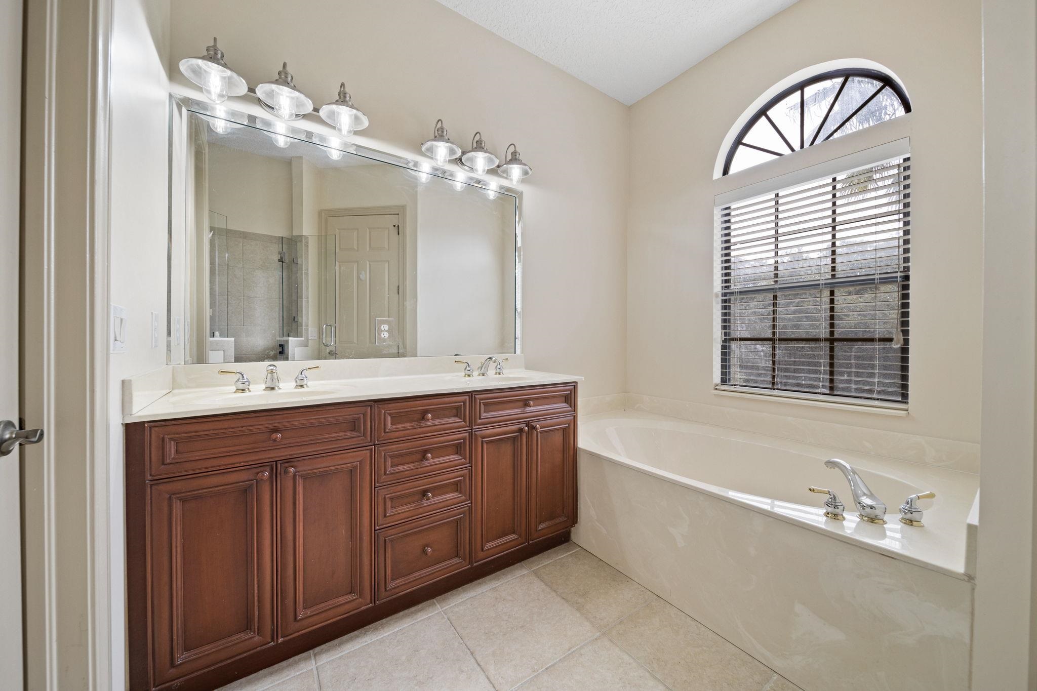 650 South Loop Street St. Augustine, FL 32095 - Photo 15 of 40 a spacious bathroom with a granite countertop tub a double vanity sink and a mirror