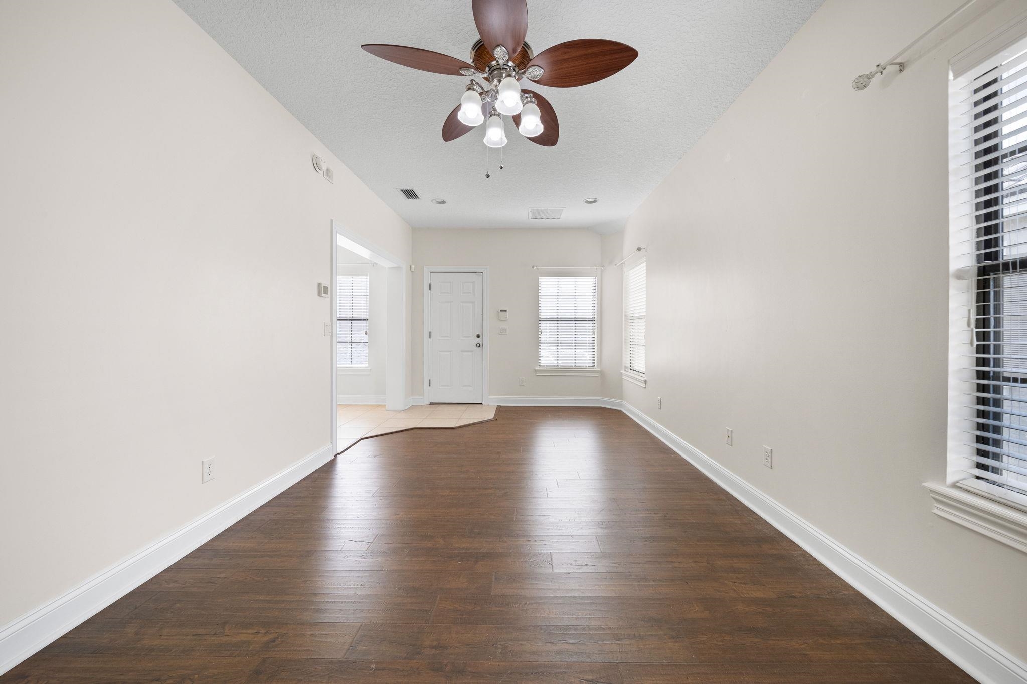 650 South Loop Street St. Augustine, FL 32095 - Photo 26 of 40 an empty room with wooden floor chandelier fan and windows