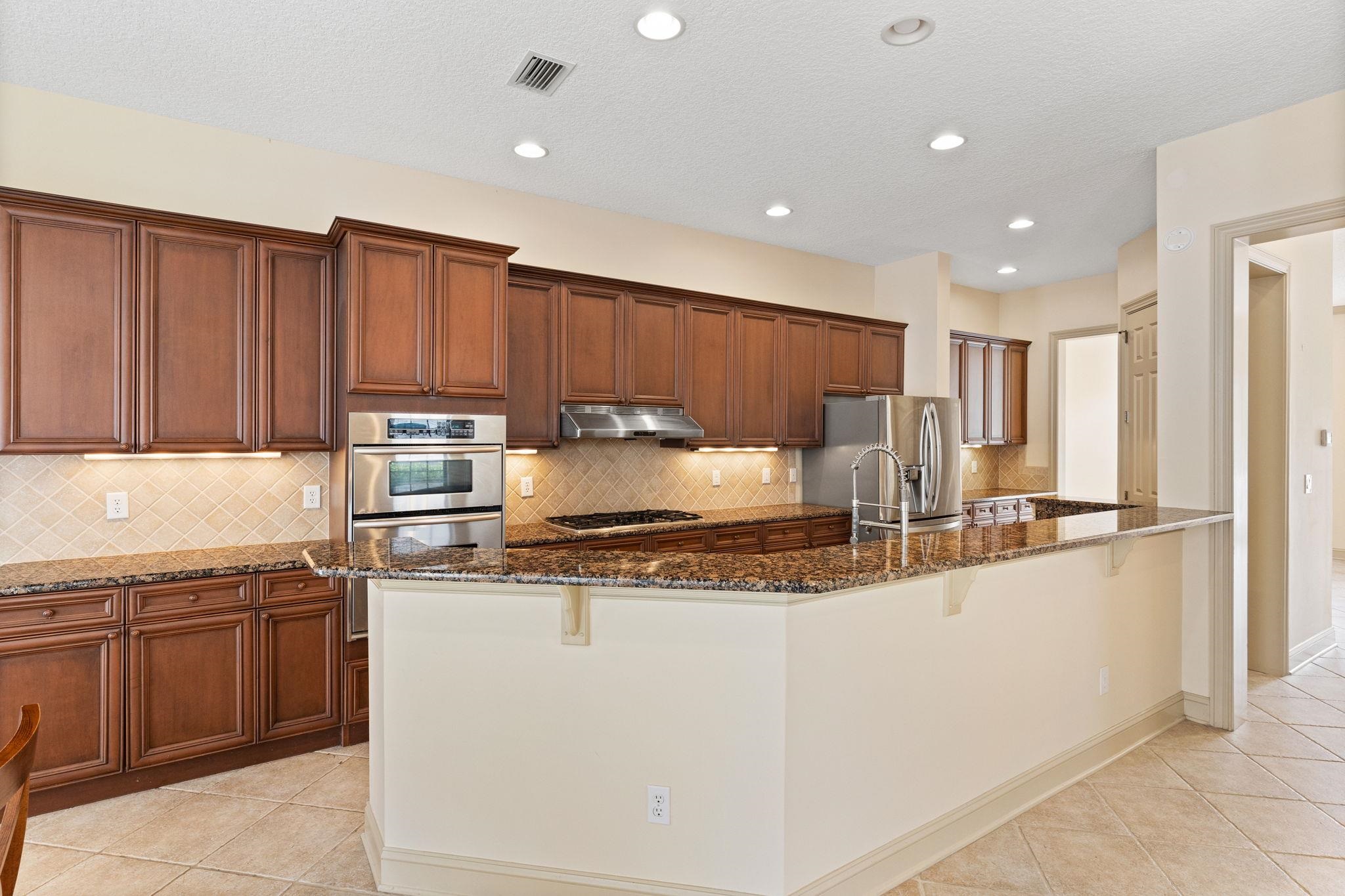 650 South Loop Street St. Augustine, FL 32095 - Photo 8 of 40 a kitchen with stainless steel appliances granite countertop a sink refrigerator and cabinets