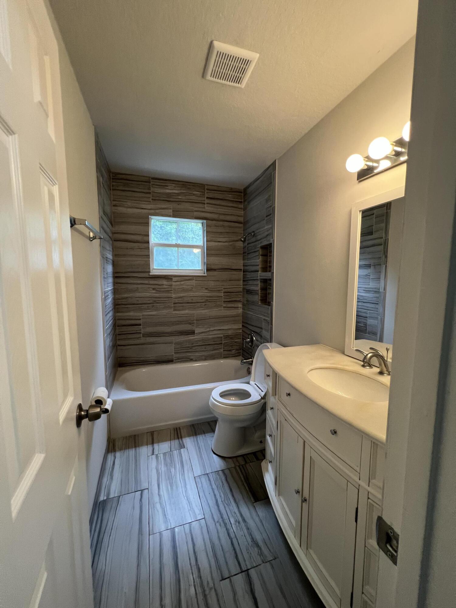 6703 Pensacola Road Fort Pierce, FL 34951 - Photo 11 of 15 a bathroom with a granite countertop toilet a sink and mirror
