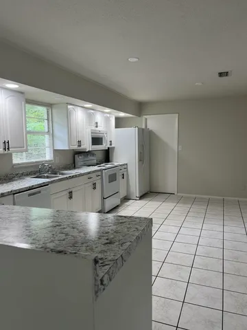 a kitchen with kitchen island granite countertop a sink stove and cabinets