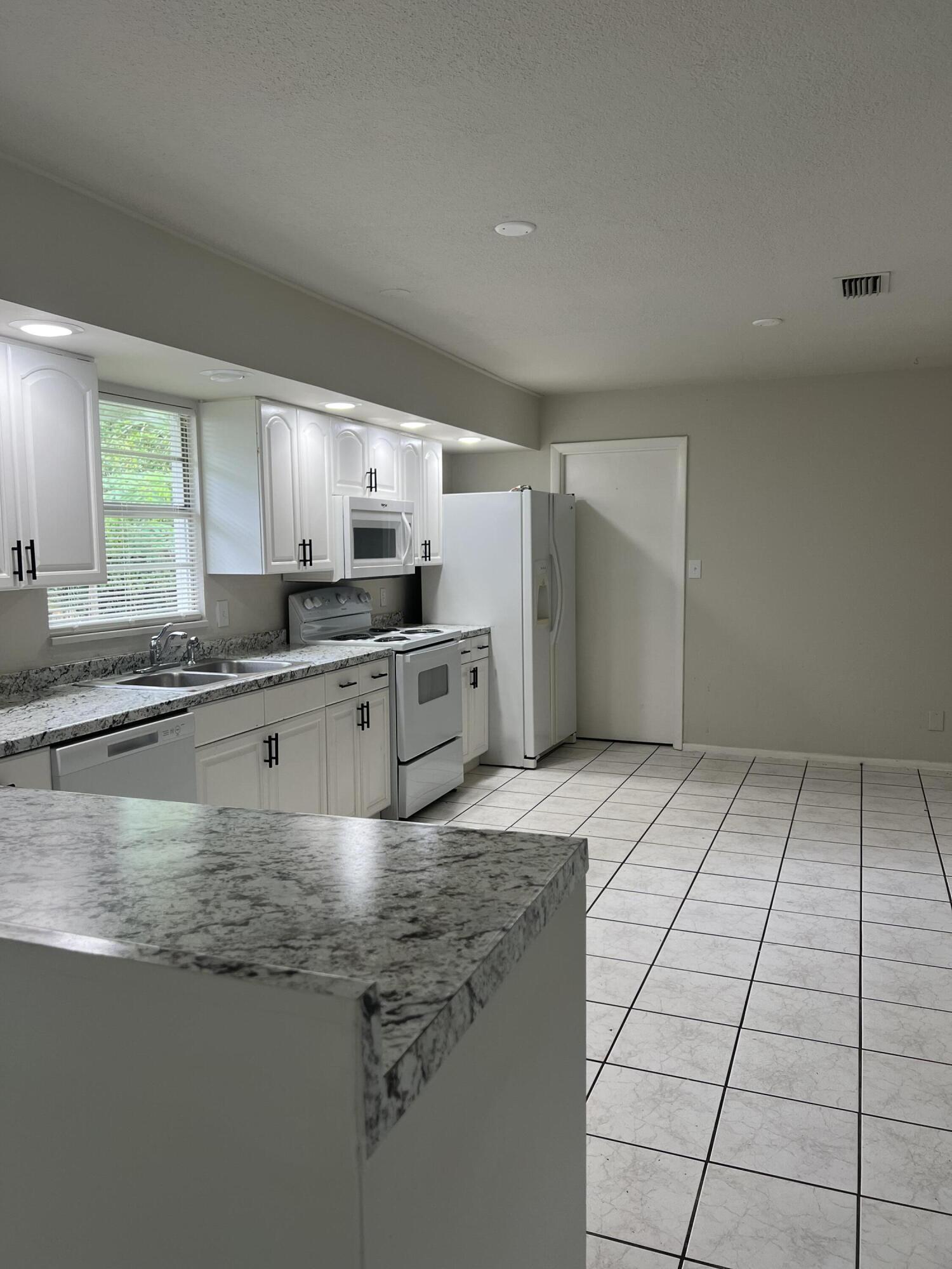 6703 Pensacola Road Fort Pierce, FL 34951 - Photo 7 of 15 a kitchen with kitchen island granite countertop a sink stove and cabinets