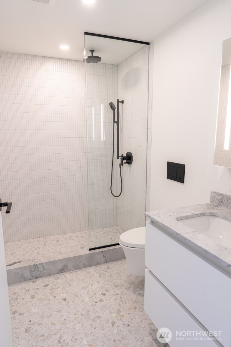 300 Virginia Street, Unit 4403 Seattle, WA 98101 - Photo 10 of 40 a bathroom with a granite countertop sink a toilet and a shower