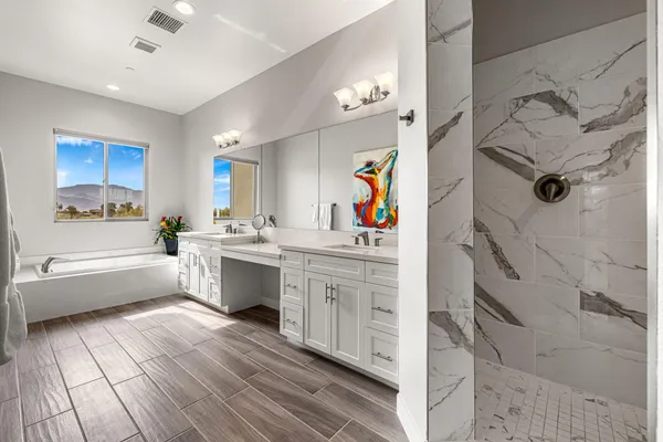 a large white kitchen with a lot of counter space and wooden floor