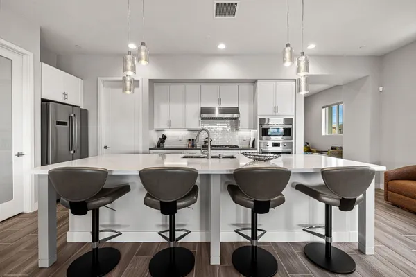 a kitchen with stainless steel appliances granite countertop a dining table chairs stove a refrigerator and cabinets