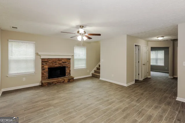 an empty room with windows a fireplace and wooden floor