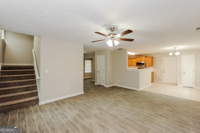 an empty room with wooden floor and a ceiling fan
