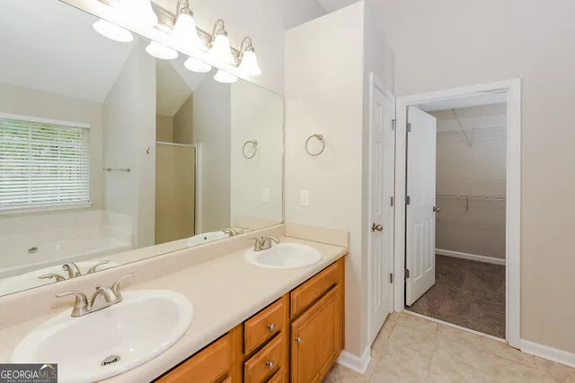 a spacious bathroom with a double vanity sink a large mirror and shower