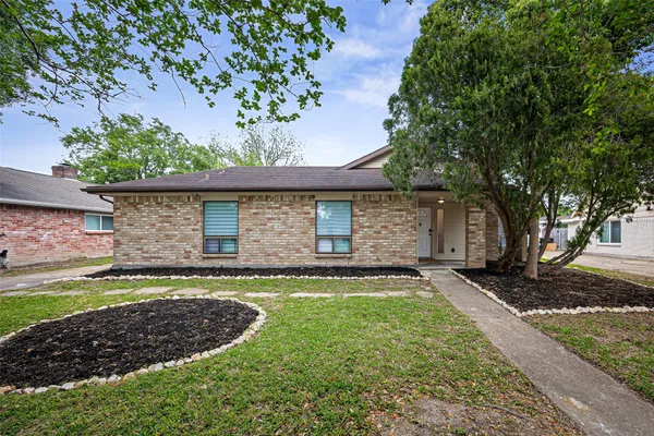 a front view of a house with a garden and trees