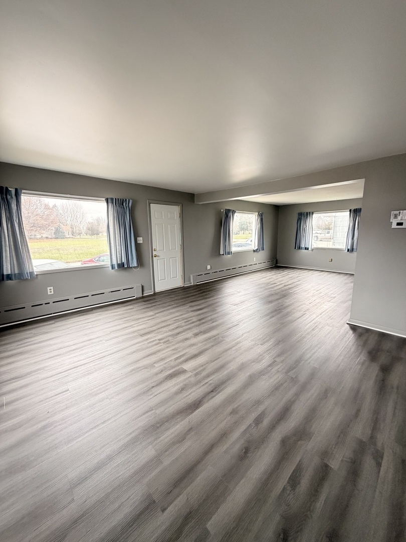 106 Main Street Lostant, IL 61334 - Photo 2 of 18 an empty room with wooden floor and windows