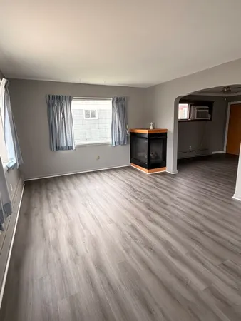 a view of an empty room with a window and wooden floor
