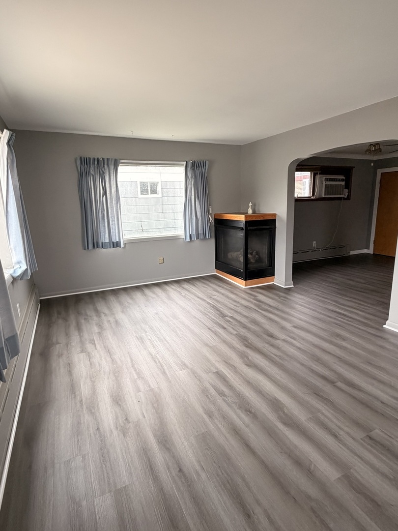 106 Main Street Lostant, IL 61334 - Photo 3 of 18 a view of an empty room with a window and wooden floor