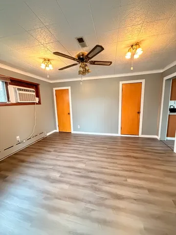 a view of a room with a ceiling fan and wooden floor