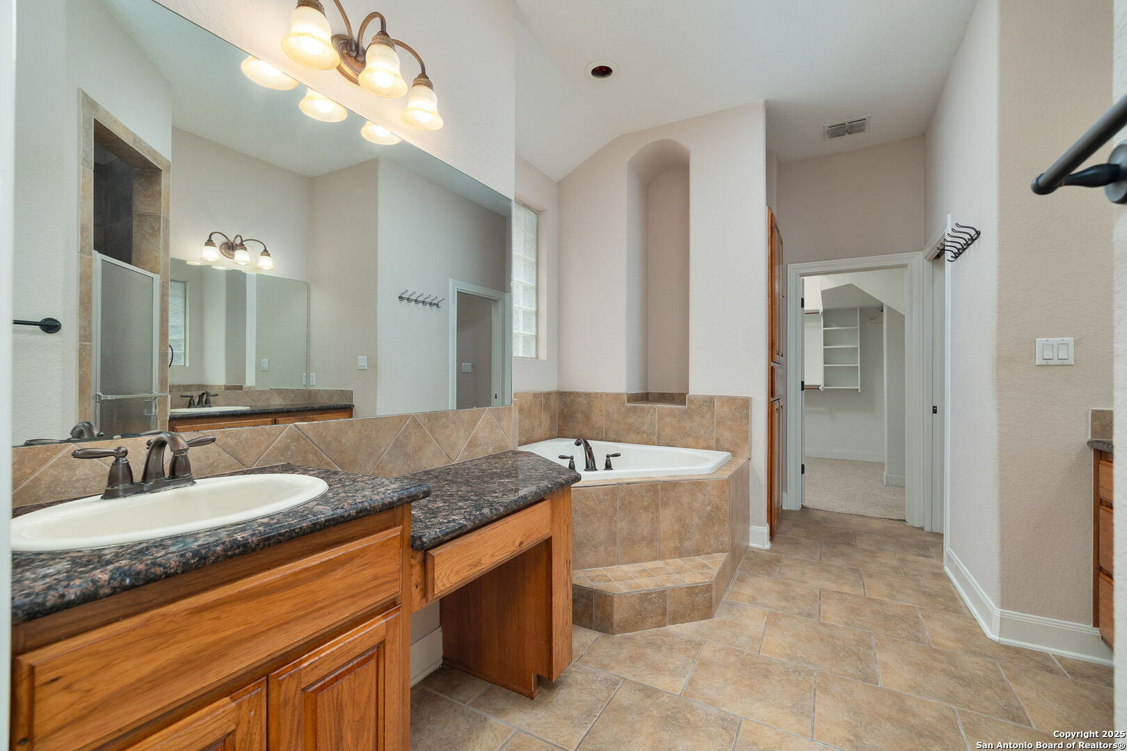 11235 Indian Caves Helotes, TX 78023 - Photo 25 of 45 a bathroom with a granite countertop double vanity sink a large mirror and a bathtub
