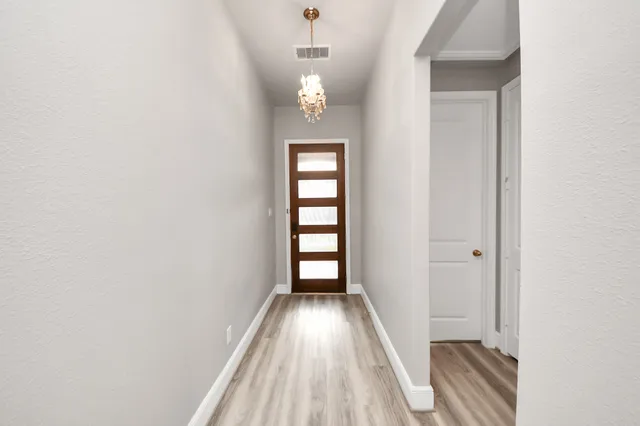 a view of hallway with walk in closet and wooden floor