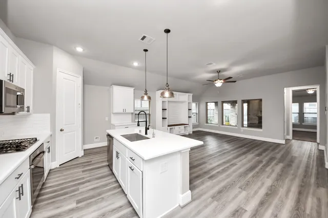 a kitchen with stainless steel appliances kitchen island a white stove top oven a sink dishwasher and a refrigerator with wooden floor