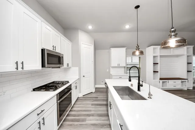 a kitchen with a sink chandelier and wooden floor