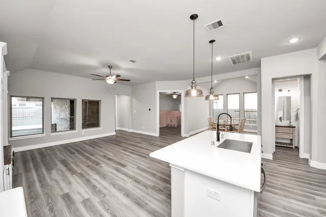 a kitchen with stainless steel appliances kitchen island granite countertop a sink a stove and a wooden floors