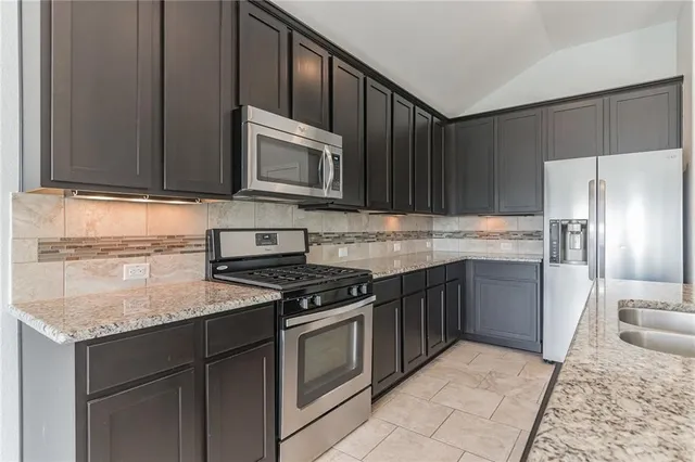 a kitchen with granite countertop a sink stove and refrigerator