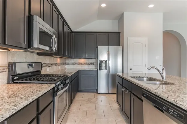 a kitchen with stainless steel appliances granite countertop a sink stove and refrigerator