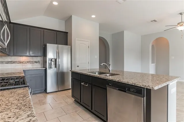 a kitchen with stainless steel appliances granite countertop a sink a stove and a refrigerator