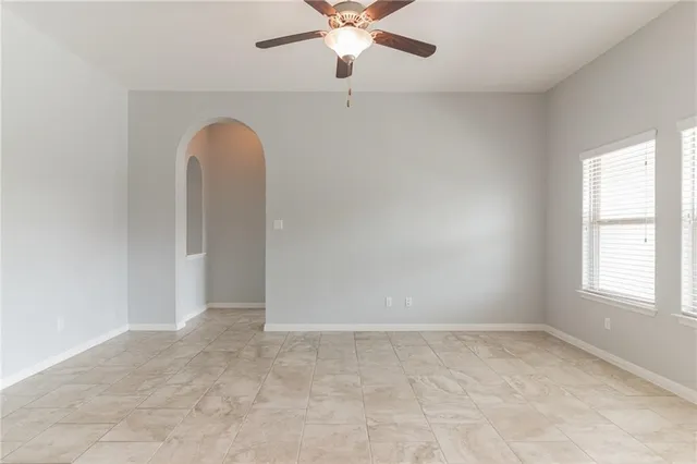 an empty room with windows and ceiling fan