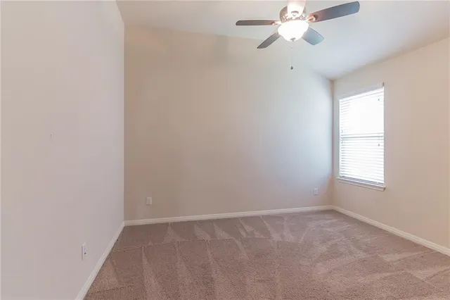 an empty room with a window and a fan