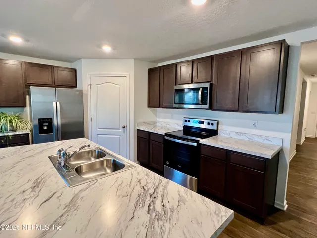 a kitchen with granite countertop wooden cabinets a refrigerator and a stove top oven