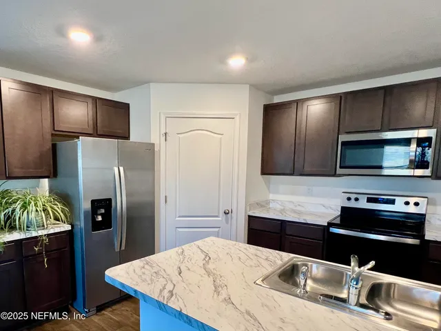 a kitchen with stainless steel appliances wooden cabinets a sink and a refrigerator