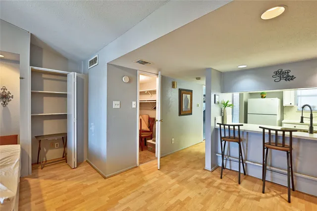 a view of a hallway with wooden floor and a bathroom