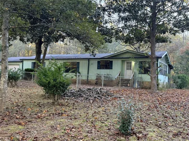 a backyard of a house with table and chairs under an umbrella
