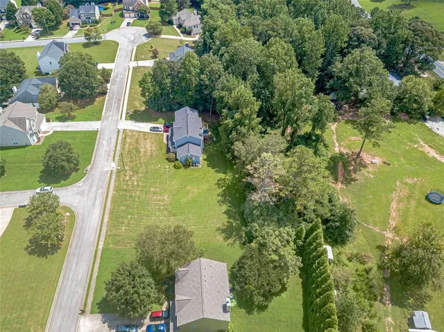 an aerial view of residential houses with outdoor space and trees