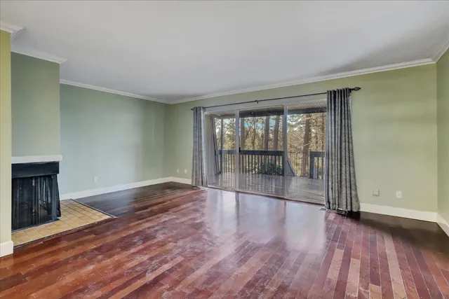 a view of an empty room with window and wooden floor