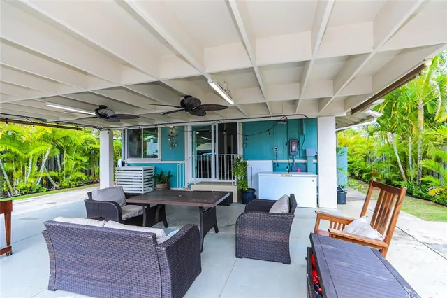 a view of a patio with couches chairs potted plants and floor to ceiling window