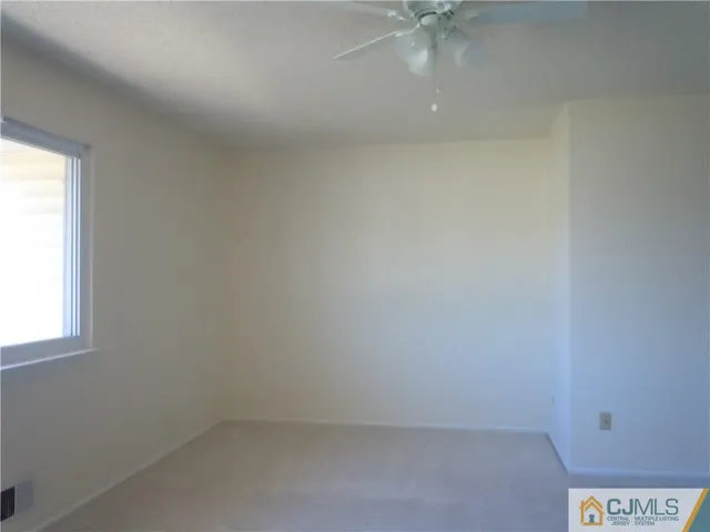 an empty room with a window and a fan