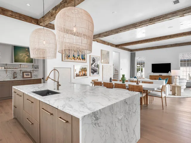 a kitchen with stainless steel appliances granite countertop a stove a refrigerator a sink a dining table and chairs with wooden floor